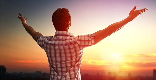 Man with outstreched arms watching sunset