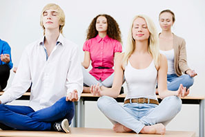 group of multi-gendered students meditating on desktops