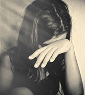 girl with dark hair with her head down and hand covering her eyes