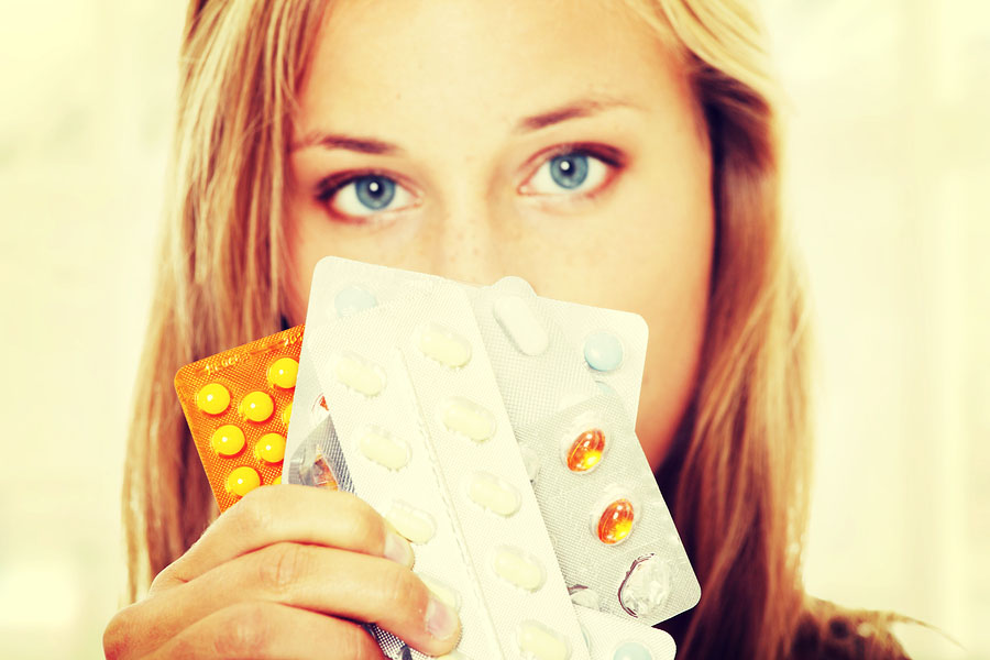 Female holding pill packets in front of her face