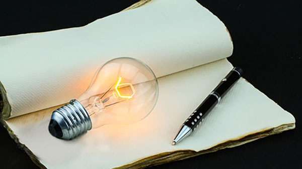 open book with a lightbulb and pen sitting on top of the pages