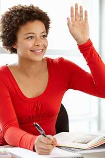 student sitting at a desk and raising her hand