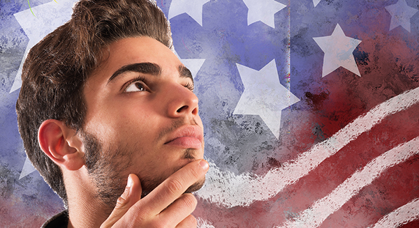 male teen looking up at an American Flag in the background