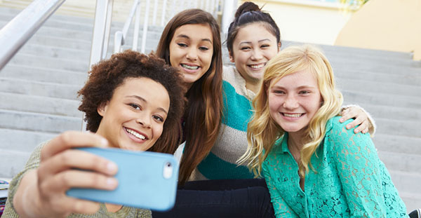 four female teens taking a selfie with a cell phone