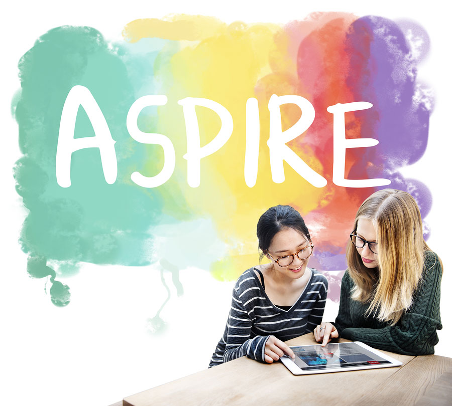 two female teens looking at a table with the word aspire behind them in the background