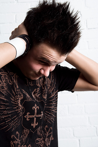 Teenage boy with his face down and hands on the side of his head