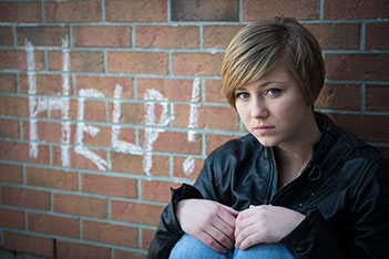 Girl sitting against brick wall 