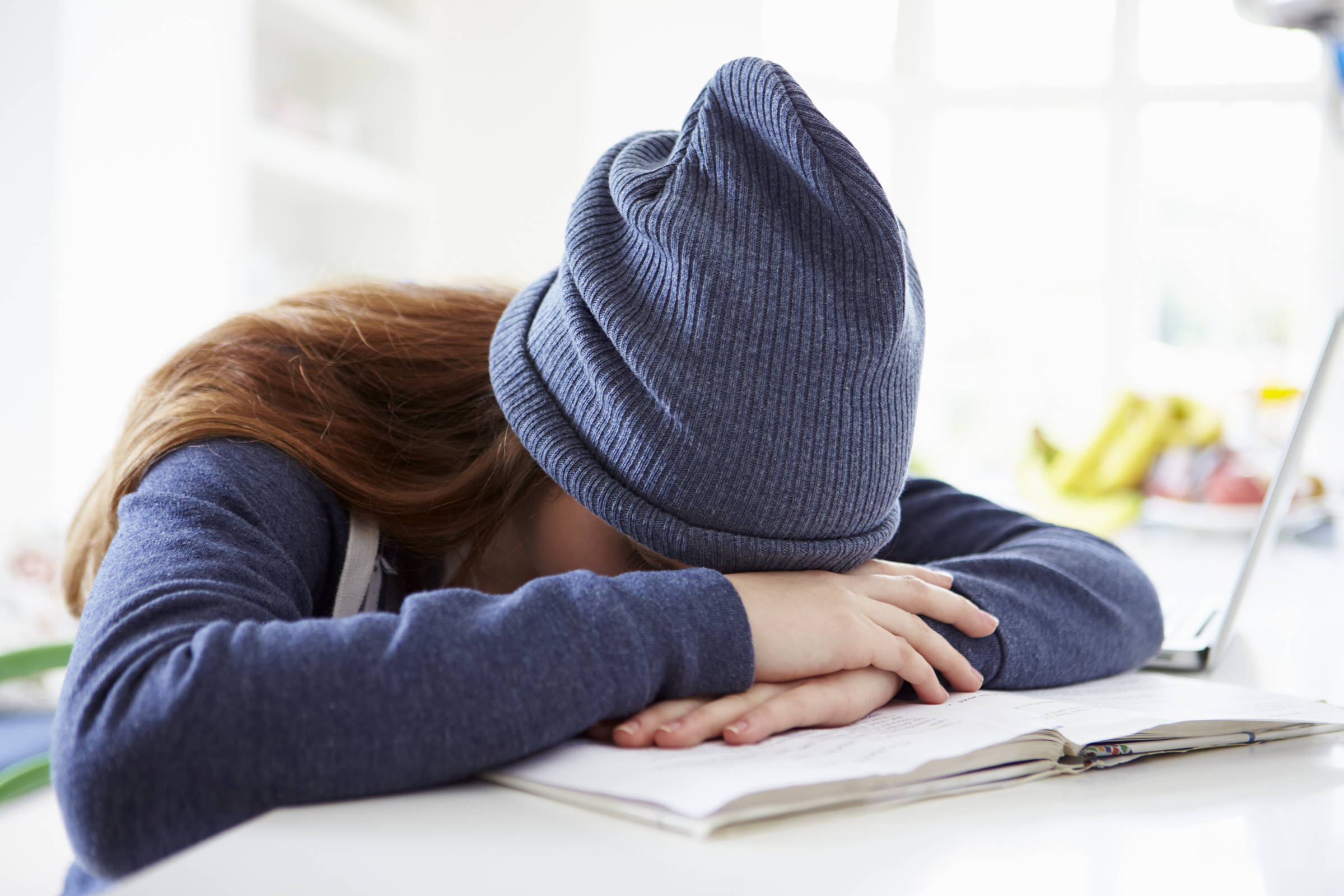 Teenager girl who has her head on her desk due to stress