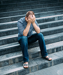 Man sitting on stairs holding his head