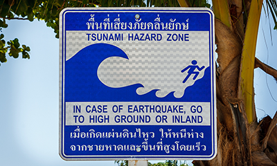 Warning sign that reads: tsunami hazard zone, in case of earthquake, go to high ground or inland