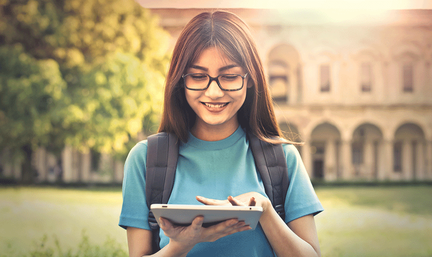 a female student standing outside and using a tablet